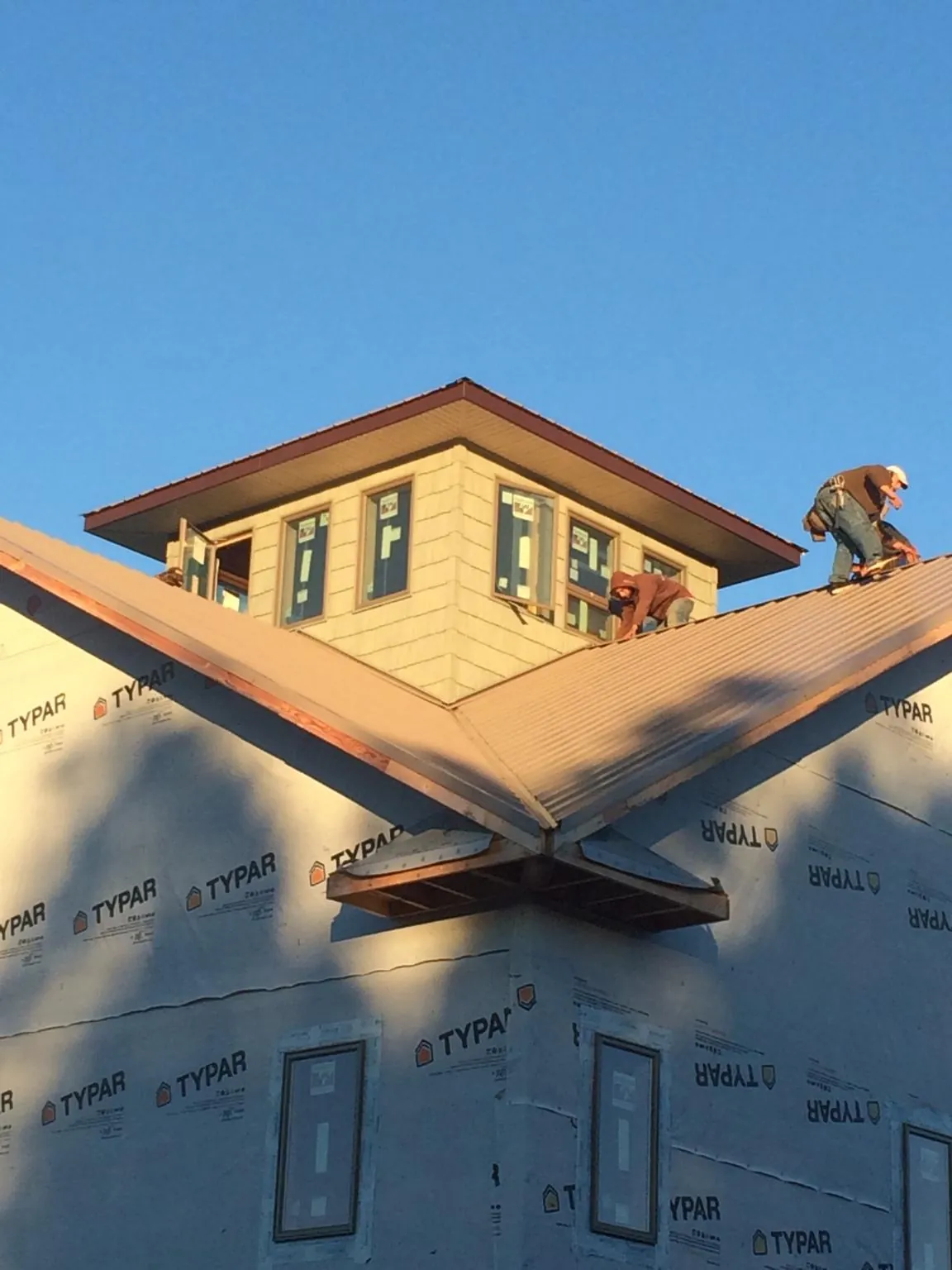 Roofers working around a rooftop cupola on a new metal roof at sunset — Roof Waterproofing in Carlisle by Roofing Brothers